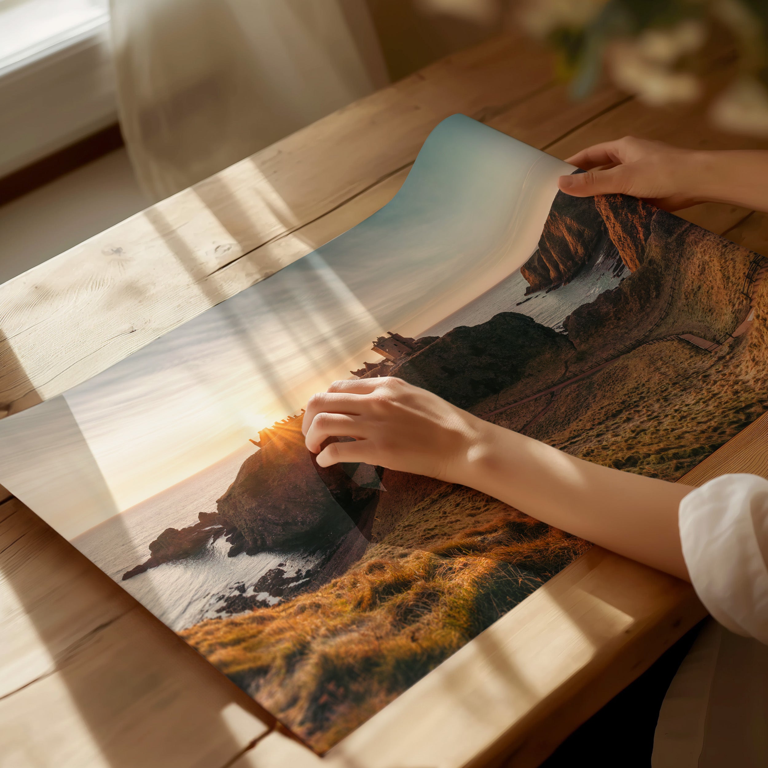 A Scottish landscape photo print being unrolled by a woman on a tabletop. 