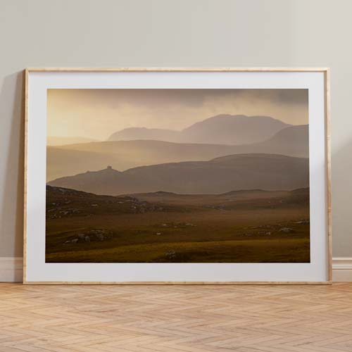 A framed photograph of a Scottish Mountain Landscape Photography Print leaning against a wall